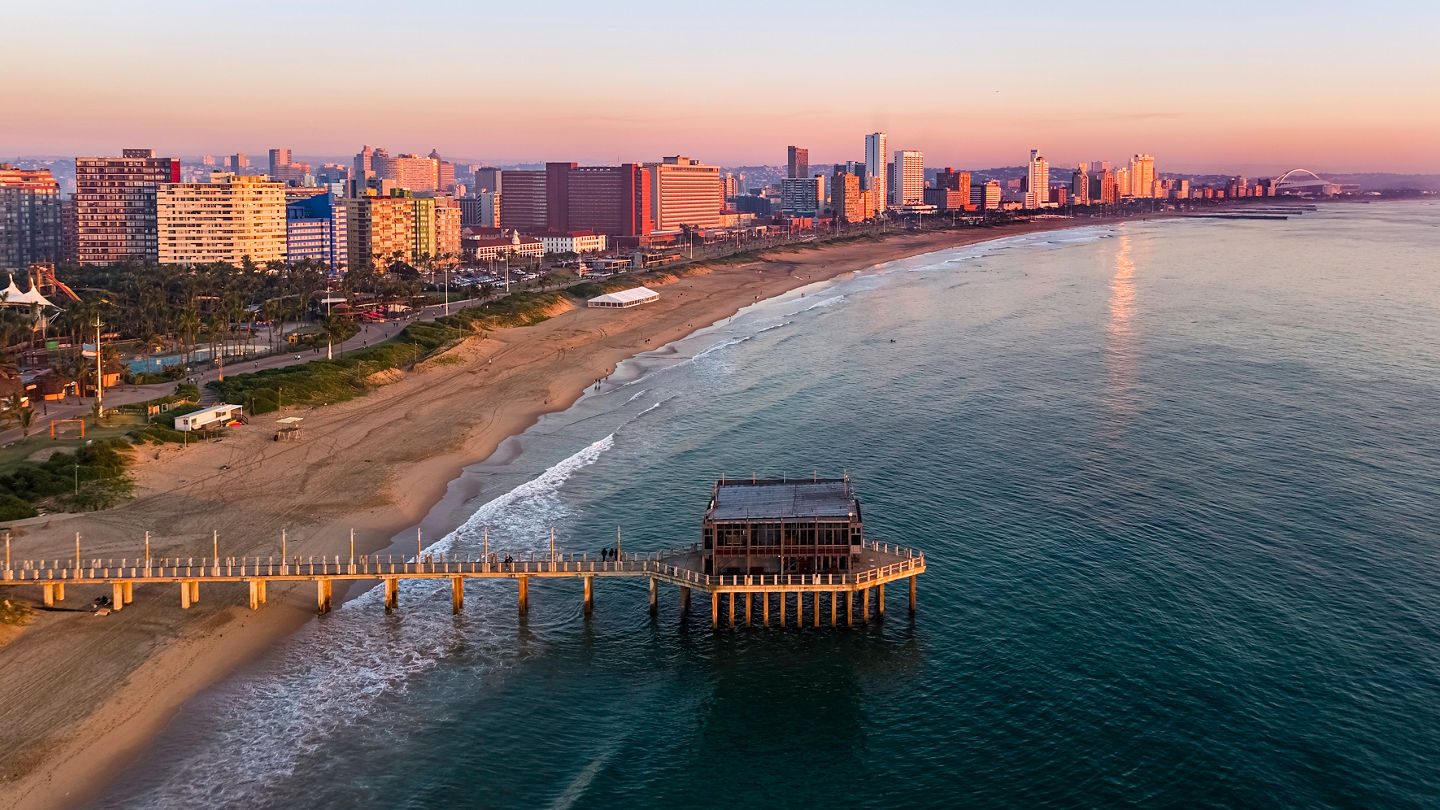 Durban cityscape seen at sunrise with a restaurant on the pier and the beaches, hotels and apartment skyscrapers at the beachfront.
