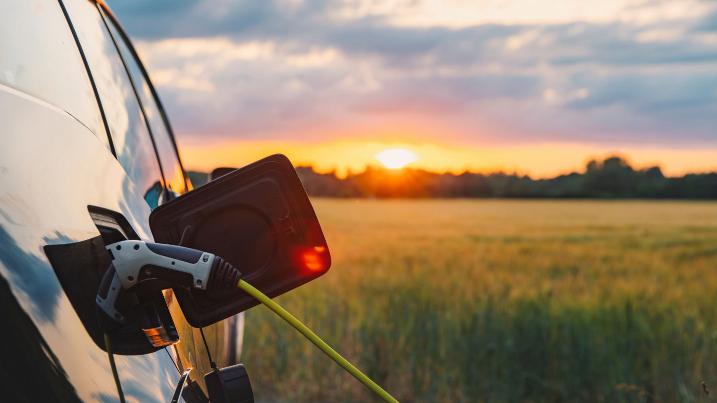 Electric car charging at sunset