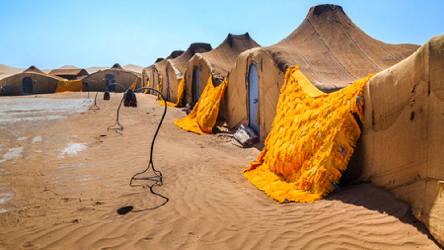 92151953 - nomadic settlement in the sahara desert .the structures all have blue doors and are made from woven cloth.