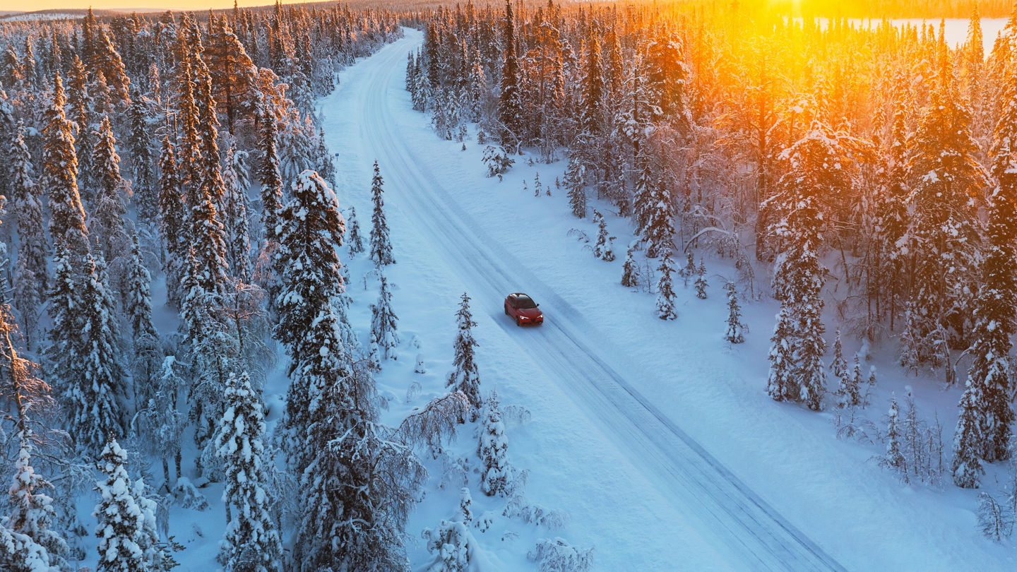 Car travels the icy and empty road crossing the boreal snowy forest at sunrise, Swedish Lapland, Sweden, Scandinavia, Europe