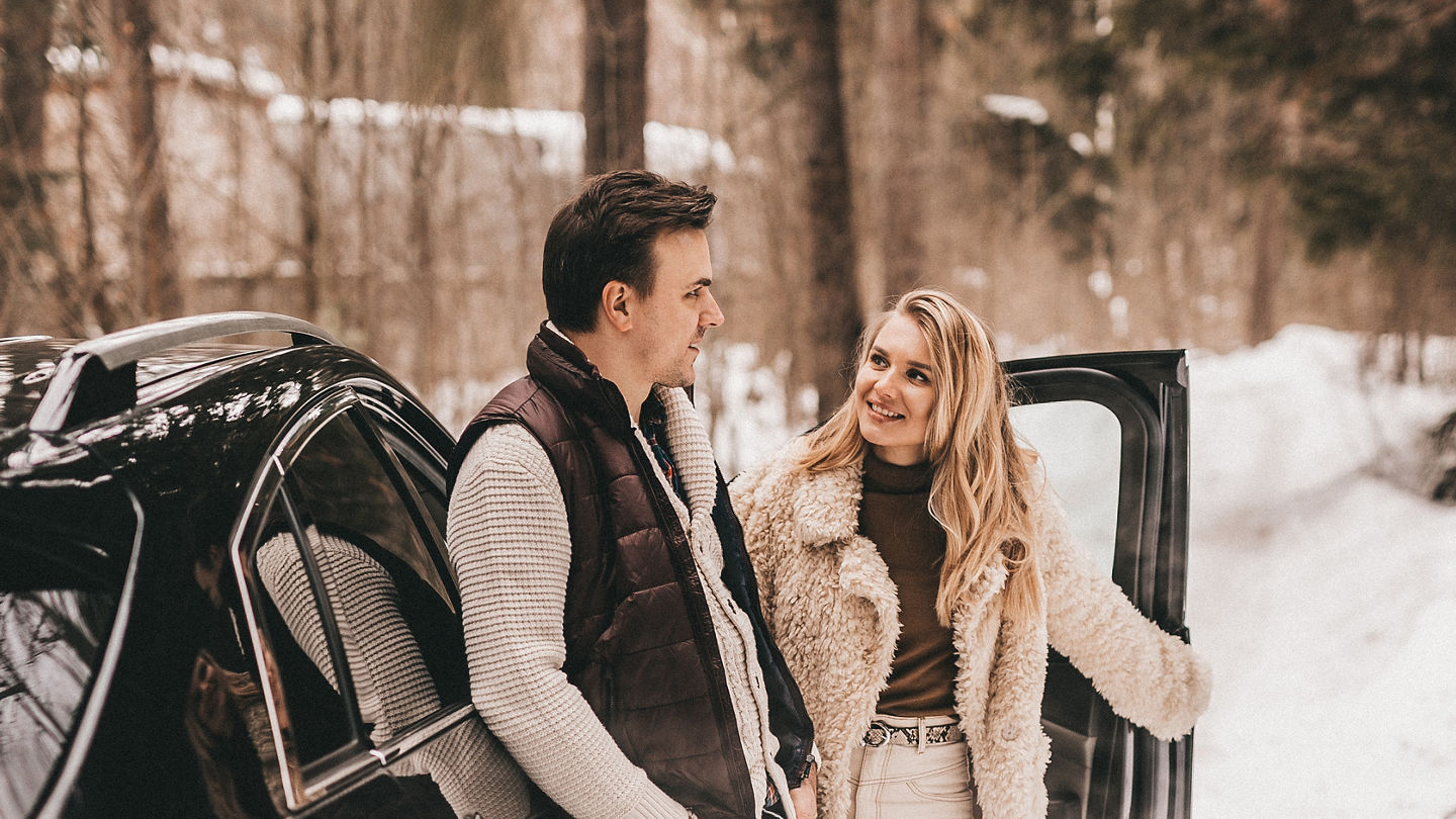 Loving couple are walking in the winter in the forest near the car, NOISE EFFECT ON PHOTOS