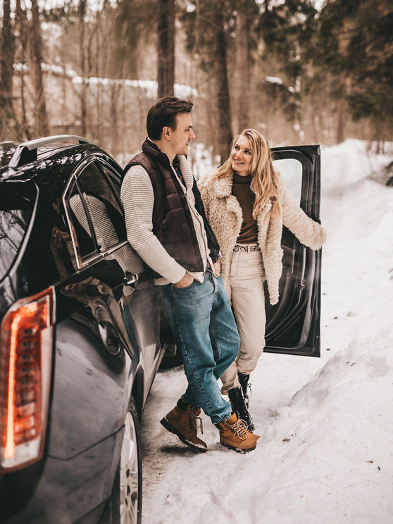 Loving couple are walking in the winter in the forest near the car, NOISE EFFECT ON PHOTOS