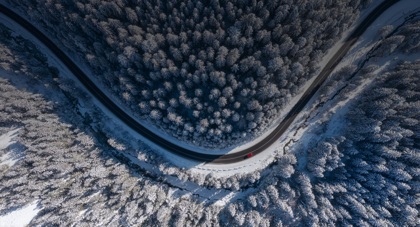 Natural winter landscape from air. Aerial view on the road and forest at the winter time. Winter chill. Forest and snow. The photo is in high resolution.