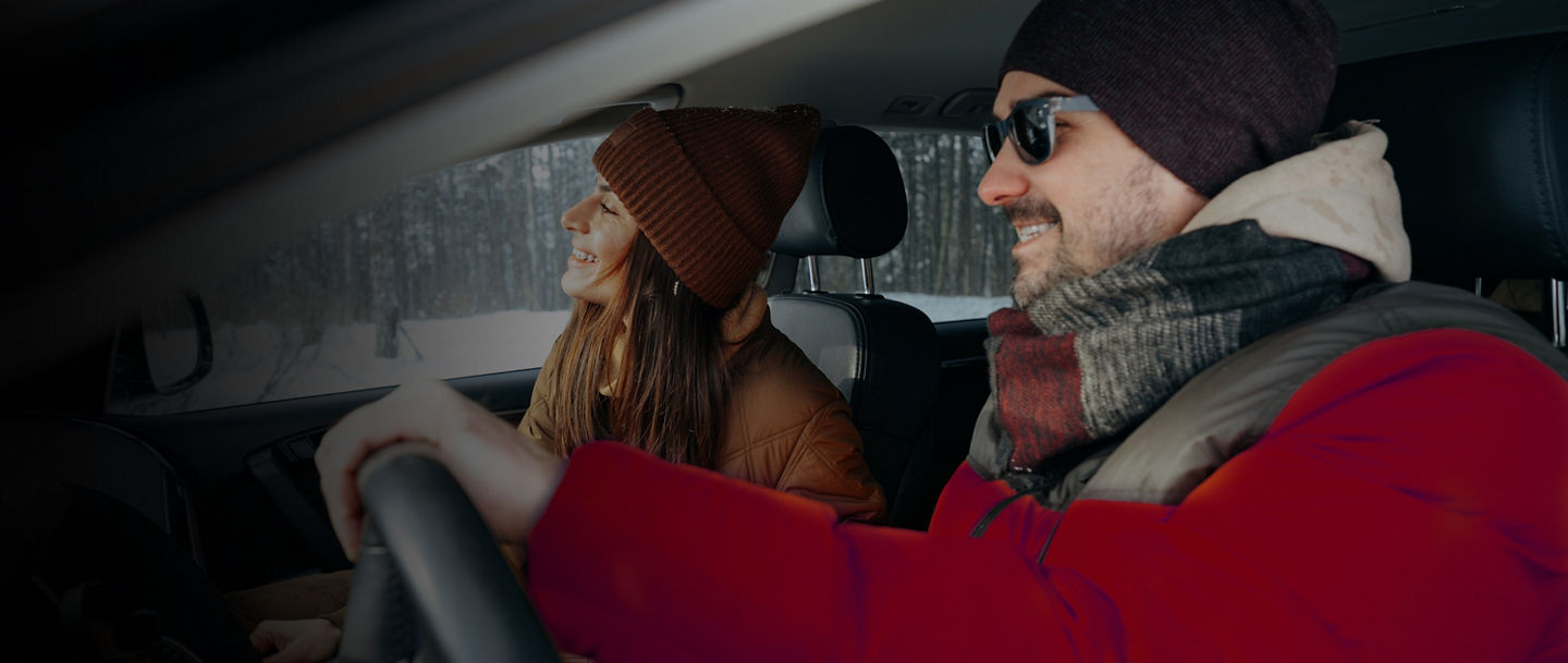Family couple sitting in car in winter clothes iin snow forest