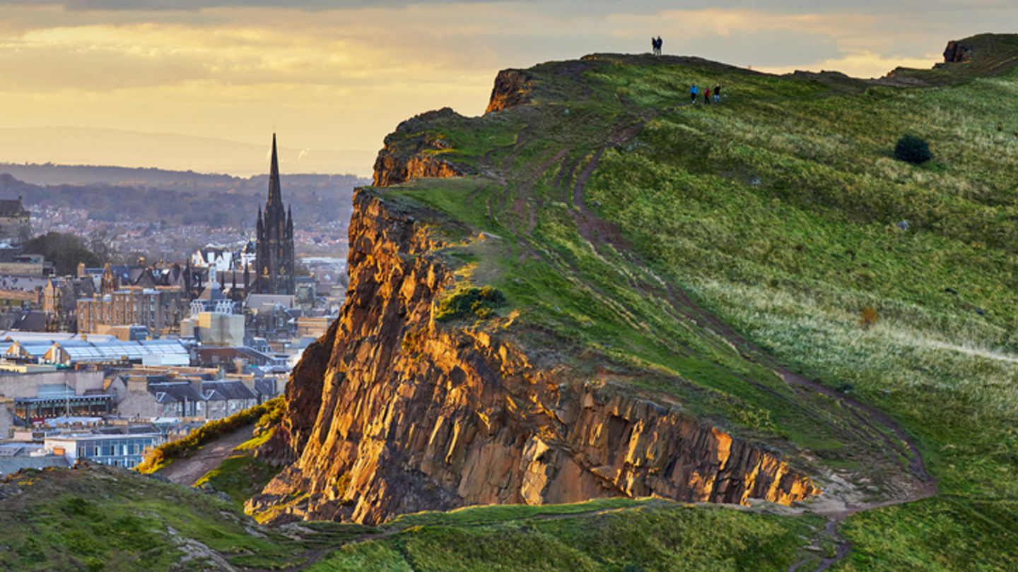Close-up of late afternoon sunlight illuminating the cliff face. St Columba's Free Church of Scotland steeple is visible