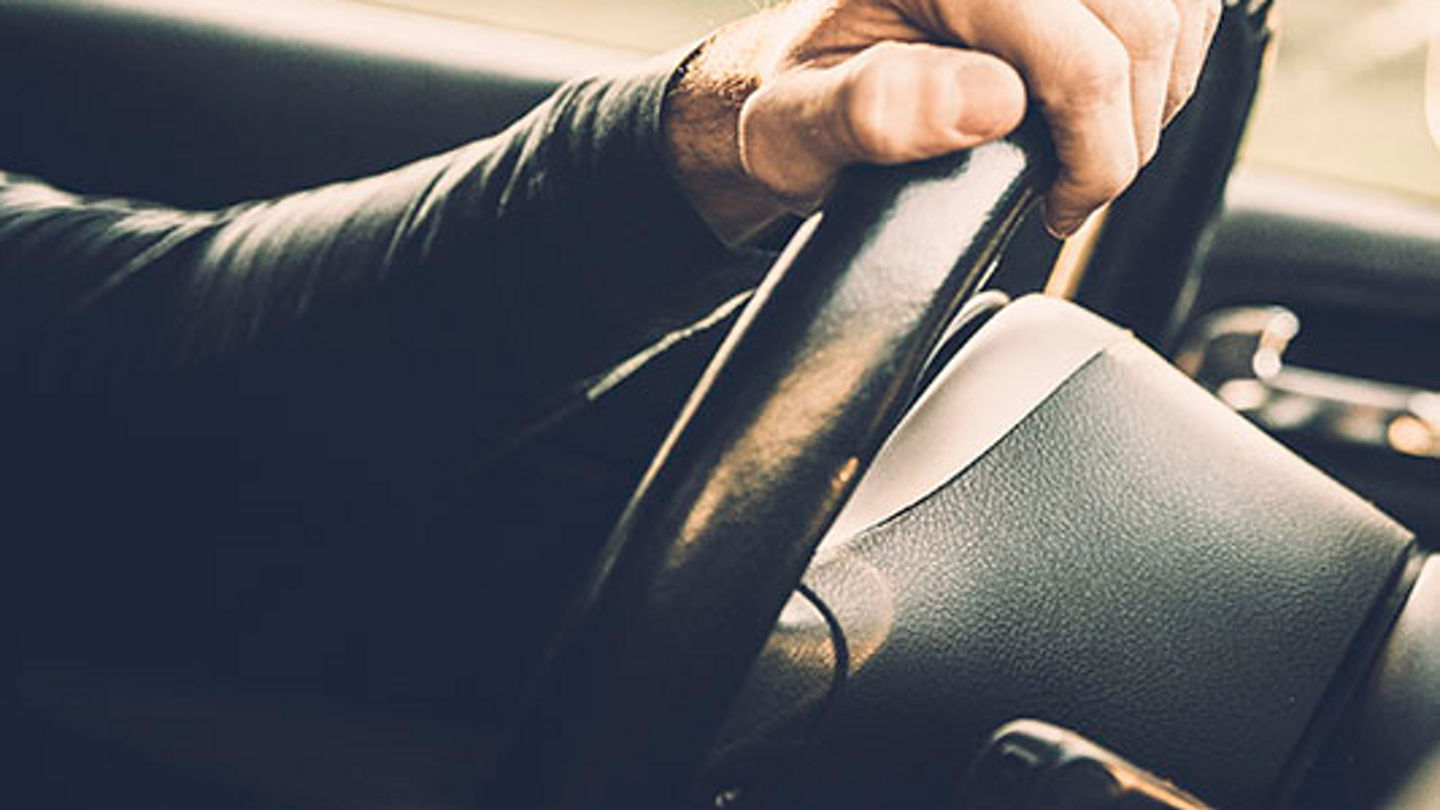 Man driving a car, close up on a steering wheel