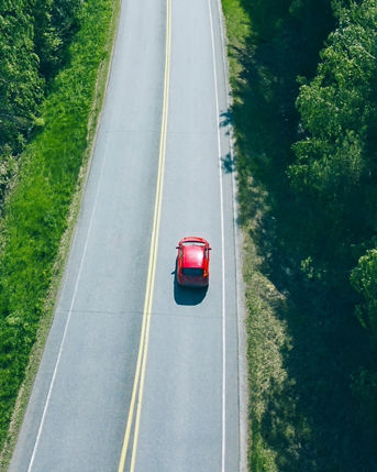 Aerial view of road with cars in green woods by blue lakes sea water in Finland