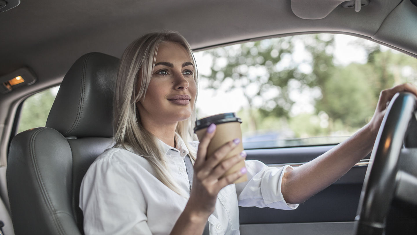 Smiling businesswoman holding takeaway coffee driving car; Shutterstock ID 746463499